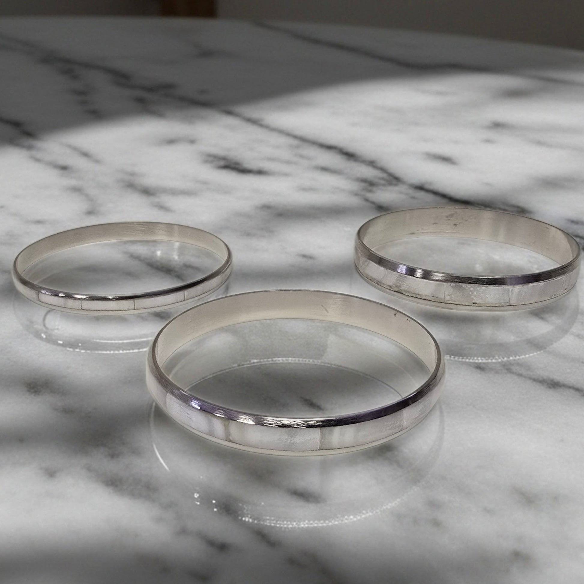 Three silver rings on a marble surface