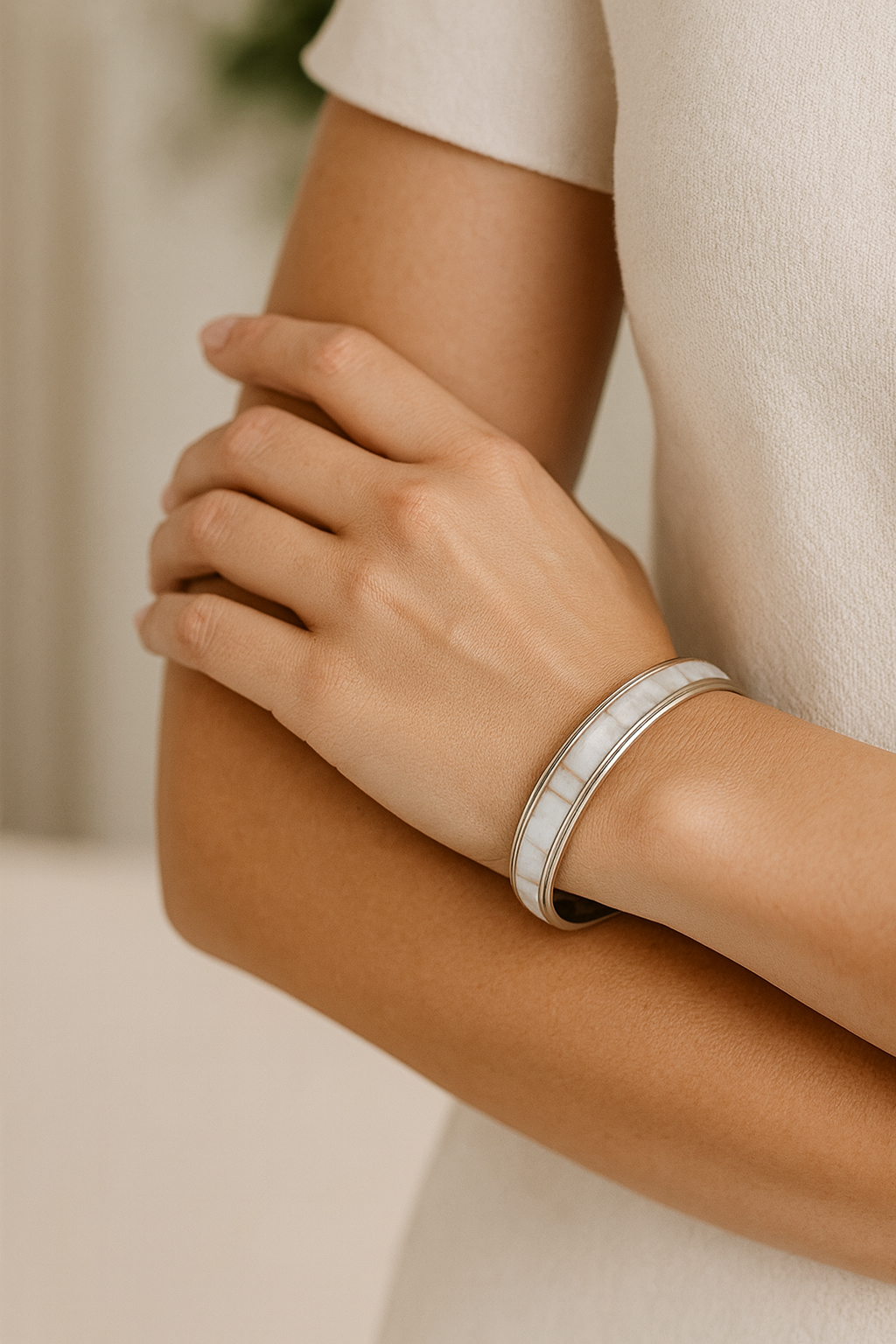 Close-up of a person's arm wearing a silver bracelet with a blurred background